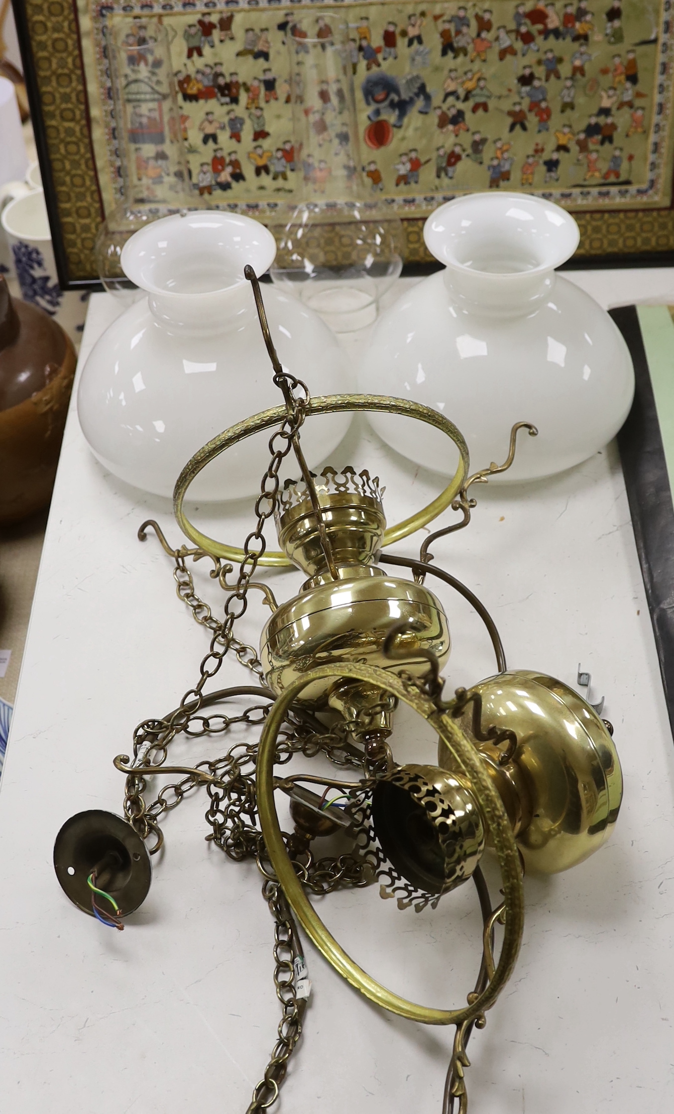A pair of brass hanging lights with opaque glass shades